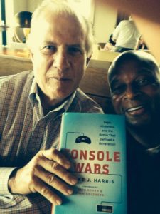 Tom Kalinske and former NFL superstar Ronnie Lott take a photo holding the "Console Wars" book.