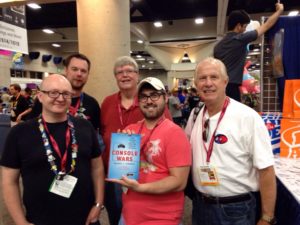 "Console Wars" author Blake Harris (center) takes a photo with Tom Kalinske (right) and Al Nilsen (back, center) during the New York Toy Fair.